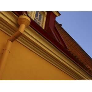 Close up of Blue Sky Behind Red Roof Tiles and Yellow Wall Molding and 